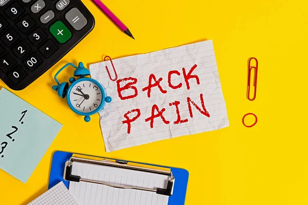Word writing text Back Pain. Business concept for Soreness of the bones felt at the lower back portion of the body Clock clips crushed note calculator pencil clipboard band color background.