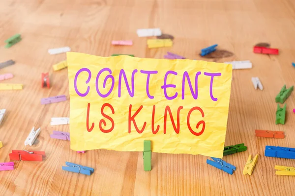 Writing note showing Content Is King. Business photo showcasing believe that content is central to the success of a website Colored clothespin papers empty reminder wooden floor background office.