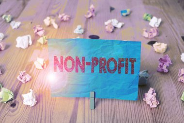 Kâr amacı gütmeyen kelime yazma metni. Sahiplerine kar getirmeyen bir organizasyon için iş konsepti. Kırışmış kağıtlar boş, ahşap zemin çamaşır mandalı..