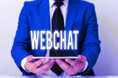 Webchat 'e mesaj yaz. Kullanıcıların gerçek zamanlı iletişim kurmasını sağlayan iş konsepti mavi süitteki internet işadamı elinde dizüstü bilgisayarla elinde tutuyor.