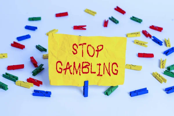 Word writing text Stop Gambling. Business concept for stop the urge to gamble continuously despite harmful costs Colored clothespin papers empty reminder white floor background office.