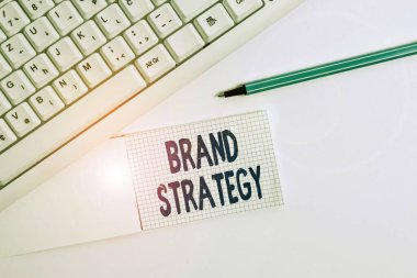 Marka Stratejisini gösteren metin işareti. Beyaz arkaplanın üzerinde boş not kağıdı bulunan başarılı bir beyaz pc klavye geliştirmek için uzun vadeli kavramsal fotoğraf planı.