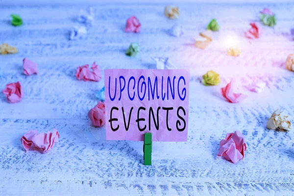 Handwriting text Upcoming Events. Concept meaning the approaching planned public or social occasions Green clothespin white wood background colored paper reminder office supply.