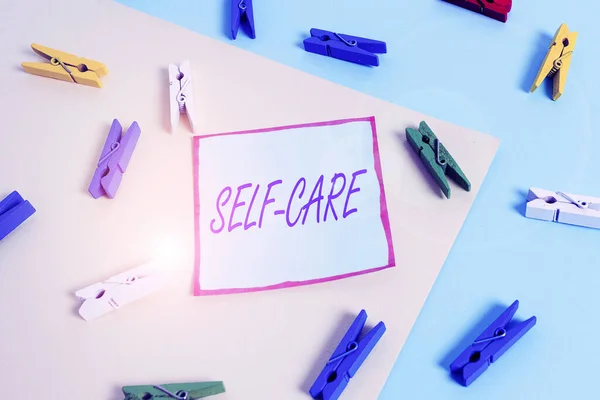Написание текста Self Care. Business concept for the practice of taking action to improve one 's is own health Colored clothespin paper empty reminder yellow blue floor background office . — стоковое фото