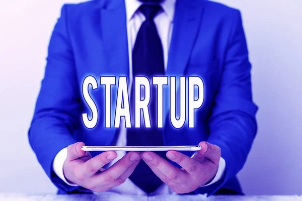 Texto de escritura de palabras Startup. Concepto de negocio para la acción de poner algo en movimiento negocios recién establecidos Empresario en suite azul con una corbata sostiene la falda en las manos . —  Fotos de Stock