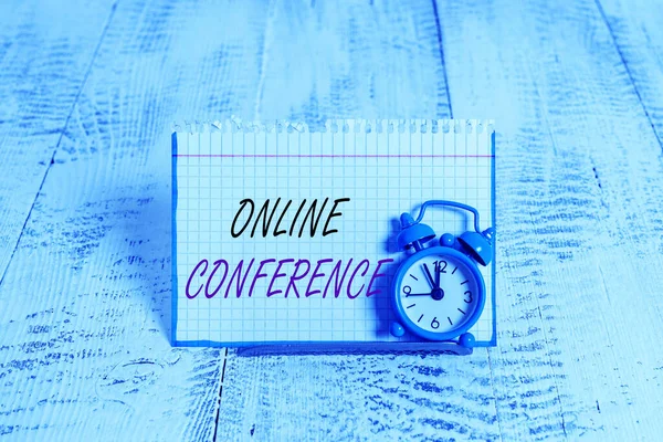 Word writing text Online Conference. Business concept for online service by which you can hold live meetings Mini blue alarm clock stand tilted above buffer wire in front of notepaper.