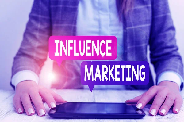 Word writing text Influence Marketing. Business concept for Using key leaders to drive a brand s is message to market Business woman sitting with mobile phone on the table.