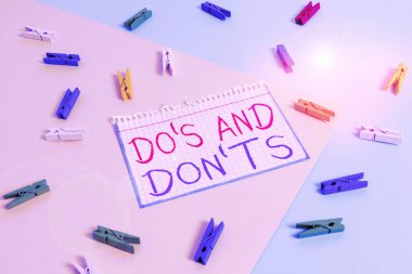 Do S ve Don 't T.S.' i gösteren bir not yazıyorum. Bazı faaliyet veya eylemlerle ilgili kural ve gelenekleri gösteren iş fotoğrafı Sarı mavi arka planlı renkli çamaşır tokası anımsatıcı.