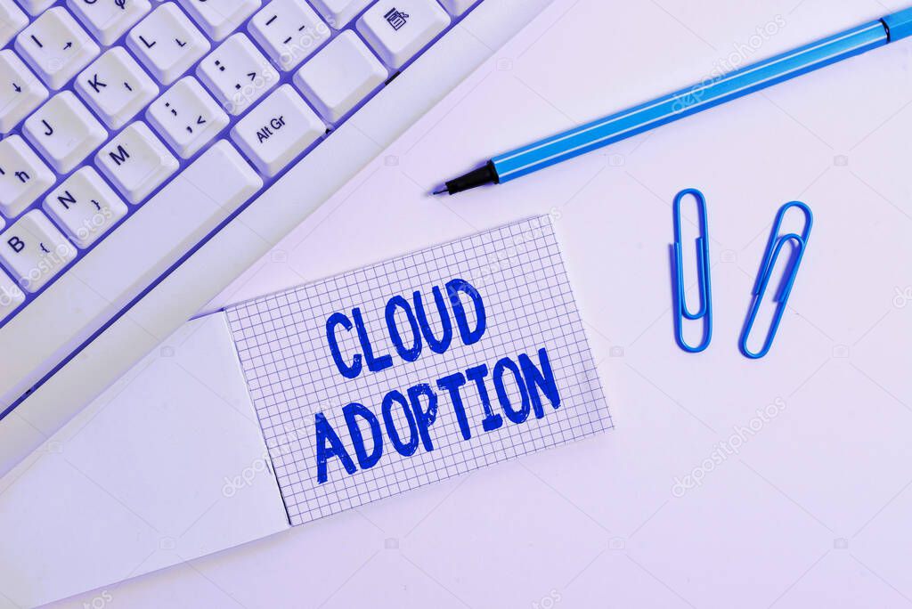 Conceptual hand writing showing Cloud Adoption. Business photo text strategic move by organisations of reducing cost and risk White pc keyboard with paper and paper clip above white background.