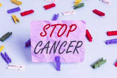 Kelime yazma kanseri durdur. Vücuttaki anormal hücrelerin kontrolsüz büyümesini önlemek için iş konsepti Renkli çamaşır iğnesi kağıtları boş mavi zemin ofis pimi.
