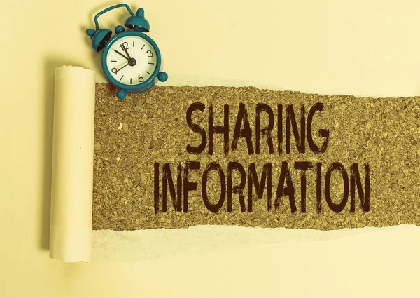 Writing note showing Sharing Information. Business photo showcasing exchange of data between various organizations Alarm clock and torn cardboard on a wooden classic table backdrop.