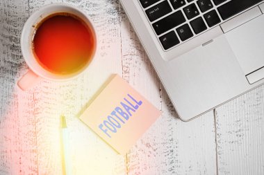 Mesajda Futbol 'u gösteriyor. Topa vurmayı içeren çeşitli takım oyunlarının kavramsal fotoğrafı. Metalik bir dizüstü bilgisayar, boş, yapışkan bir kahve fincanı. Eski model bir masa..