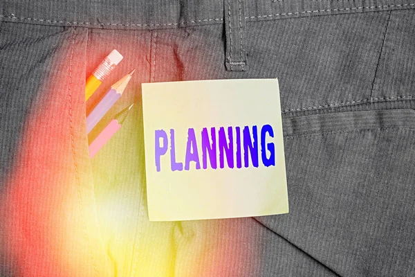 Writing note showing Planning. Business photo showcasing process of thinking about the activities required to achieve a goal Writing equipment and green note paper in pocket of trousers. — Stock Photo, Image