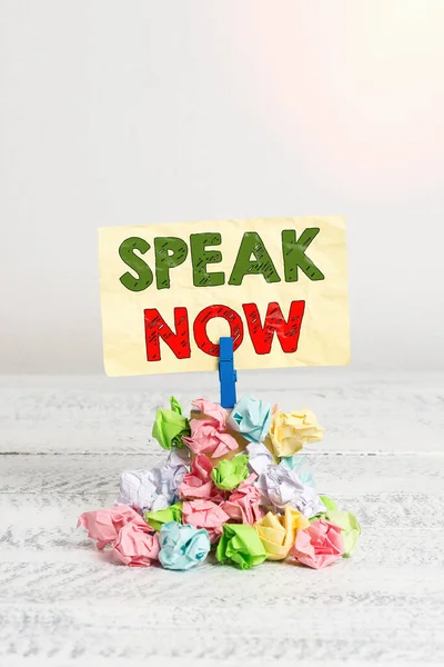 Word writing text Speak Now. Business concept for Communicate to us your feelings and information Voice out Reminder pile colored crumpled paper clothespin reminder white wooden space.