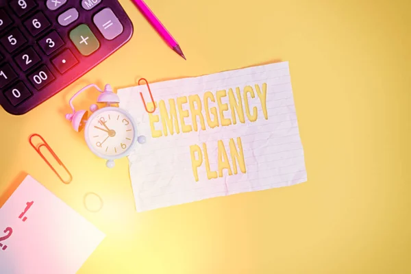 Text sign showing Emergency Plan. Conceptual photo instructions that outlines what workers should do in danger Alarm clock clips note rubber band calculator pencil colored background.