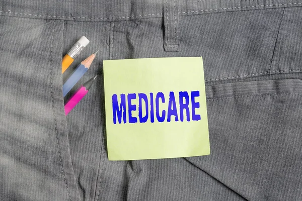 Writing note showing Medicare. Business photo showcasing the federal government plan in US for paying certain hospital Writing equipment and green note paper in pocket of trousers. — Stock Photo, Image
