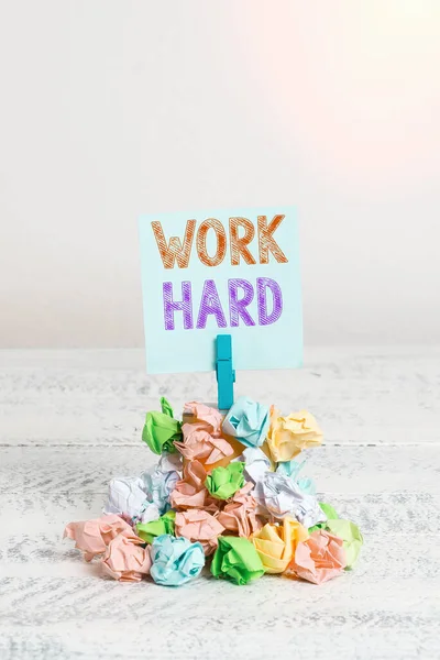 Text sign showing Work Hard. Conceptual photo Laboring that puts effort into doing and completing tasks Reminder pile colored crumpled paper clothespin reminder white wooden space. — Stock Photo, Image