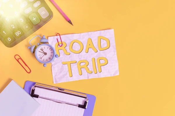 Writing note showing Road Trip. Business photo showcasing long distance journey on the road traveled by automobile Alarm clock crushed note calculator pencil clipboard color background.