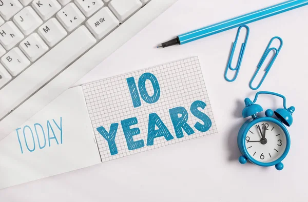 Notiz über 10 Jahre. Business-Foto präsentiert Erinnerung oder Ehrung besonderer Tag für sein 10-jähriges Bestehen Weiße PC-Tastatur mit Büroklammer über weißem Hintergrund. — Stockfoto