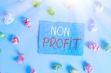 Non Profit 'i gösteren bir not yazıyorum. Sahiplerine kar getirmeyen iş fotoğrafçılığı tipi bir organizasyon. Kırışmış dikdörtgen şeklinde renkli hatırlatıcı kağıt açık mavi arkaplan..