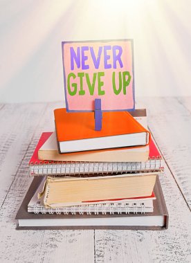 Asla Pes Etme 'yi gösteren bir not yazıyorum. İş fotoğraflarının gösterildiği bölümde, yığılmış durumdaki kitapların, not defterlerinin, renk broşlarının, beyaz ahşabın geliştirilmesinde ısrarcı olun..