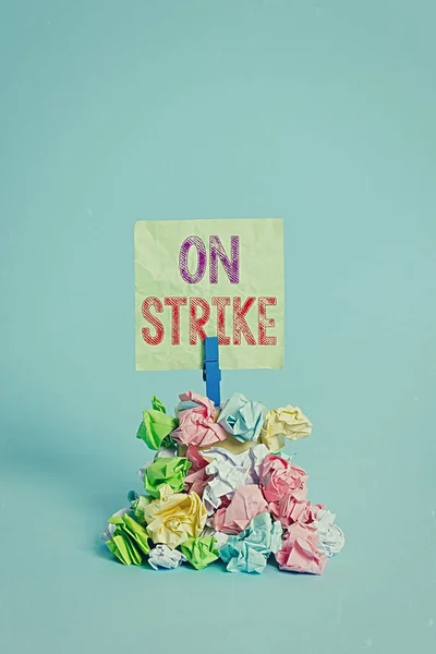 Teksten met On Strike erop. Conceptuele foto weigeren te blijven werken als gevolg van een ruzie met een werkgever Herinnering stapel gekleurde verfrommeld papier wasknijper herinnering blauwe achtergrond. — Stockfoto