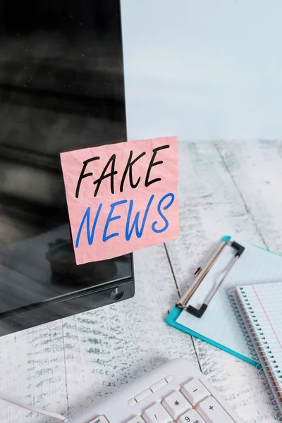 Textschild mit Fake News. Konzeptionelle Foto falsche Informationen veröffentlichen unter dem Deckmantel der Authentizität Nachrichten Notizpapier auf schwarzen Computerbildschirm in der Nähe von Tastatur und stationären geklebt. — Stockfoto