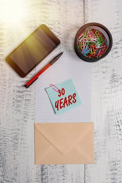 Texte écrit 30 ans. Concept d'entreprise pour se souvenir ou honorer jour spécial pour être 30 ans d'existence Smartphone porte-trombones papier stylo enveloppe note arrière-plan en bois . — Photo