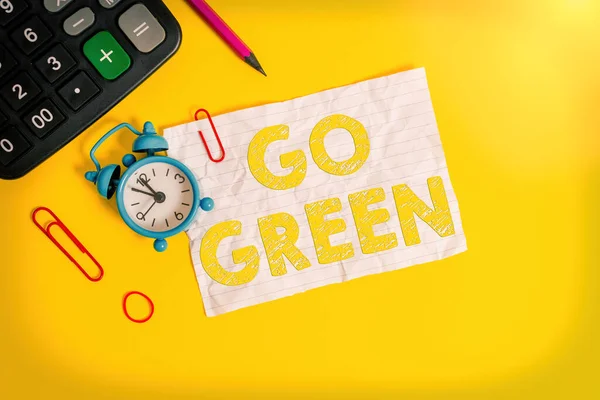 Handstil text skriva Go Green. Begreppet innebär att göra mer miljövänliga beslut som minska återvinna väckarklocka klipp not gummiband kalkylator penna färgad bakgrund. — Stockfoto