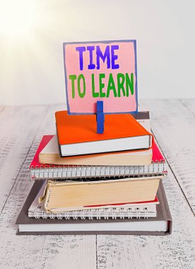 Öğrenme Zamanını gösteren not yazılıyor. Bilgi edinme ya da gerçekleri anlama ihtiyacını gözler önüne seren iş fotoğrafı yığılmış kitap, defter, renk, hatırlatıcı beyaz ahşap..