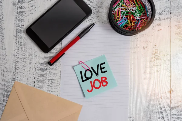 Handwriting text Love Job. Concept meaning designed to help locate a fulfilling job that is right for us Smartphone paper sheet clips holder pen envelope note wooden background.