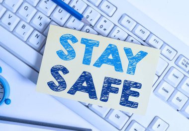 Stay Safe 'i gösteren bir not yazıyorum. İş fotoğrafı gösterimi tehlike, zarar ya da makaleleri beyaz pc klavye kağıdı ve ataçlarını beyaz arkaplanın üzerinde tutma tehdidinden güvenli.