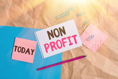 Non Profit 'i gösteren kavramsal el yazısı. Şirket sahiplerine Papercraft masa karesi spiral defter ofis malzemeleri için kâr etmeyen iş metni tipi bir organizasyon..