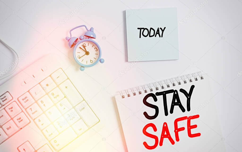 Word writing text Stay Safe. Business concept for secure from threat of danger, harm or place to keep articles White pc keyboard with empty note paper and pencil above white background.