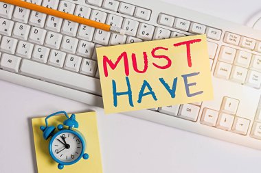 Must Have Have 'ı gösteren bir not yazıyorum. İş fotoğrafında modern bir şey gösteriliyor. Pek çok gösterici, temel ögenin pc klavye ve saat üzerindeki boş not kağıdının üzerinde durmasını istiyor..