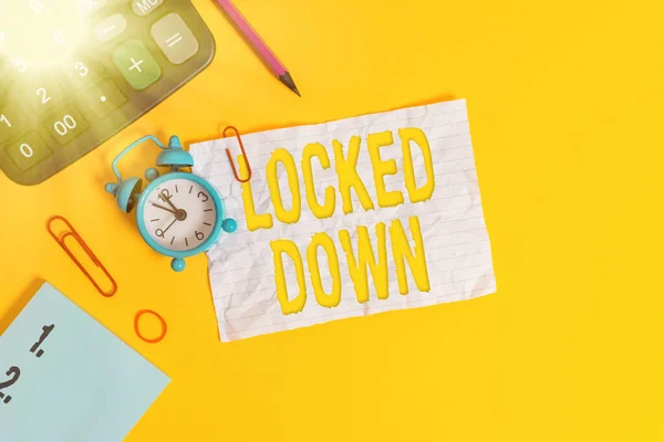 Text sign showing Locked Down. Conceptual photo emergency measure which showing prevented from restricted area Alarm clock clips note rubber band calculator pencil colored background.