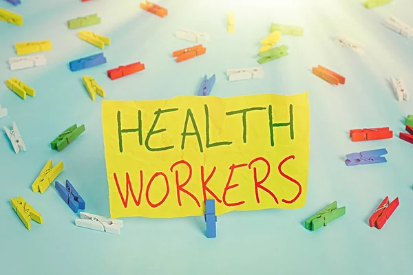 Handwriting text writing Health Workers. Concept meaning showing whose job to protect the health of their communities Colored clothespin papers empty reminder blue floor background office pin.