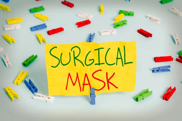 Handwriting text writing Surgical Mask. Concept meaning worn by health professionals during surgery and during nursing Colored clothespin papers empty reminder blue floor background office pin.