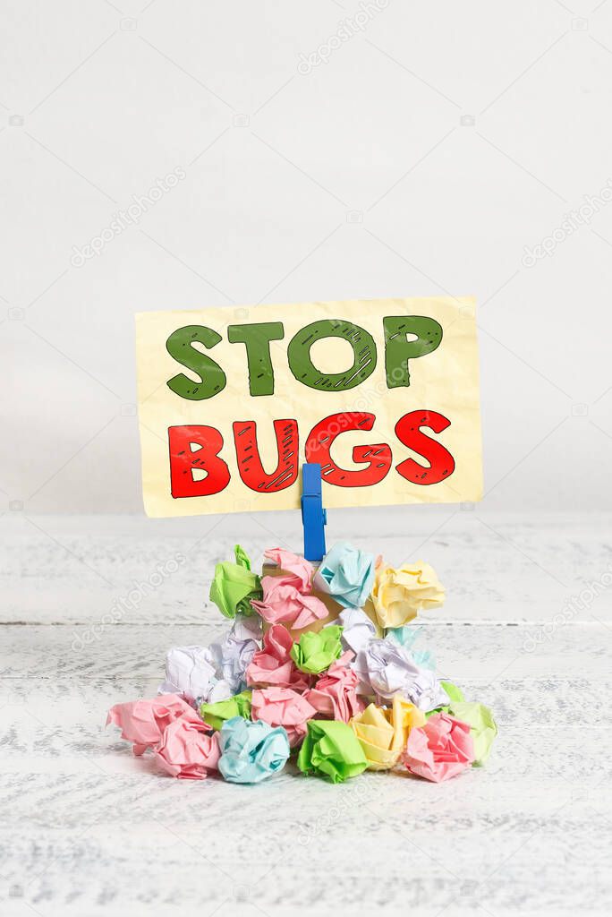 Word writing text Stop Bugs. Business concept for Get rid an insect or similar small creature that sucks blood Reminder pile colored crumpled paper clothespin reminder white wooden space.