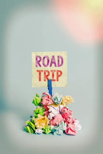 ロードトリップを示すテキスト記号。自動車で移動する道路上の概念的な写真の長距離の旅リマインダ杭色の折り目のついた紙の布ピンリマインダー青の背景. — ストック写真