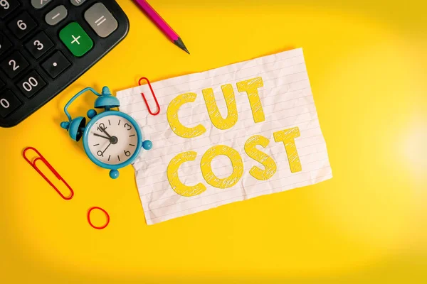 Handwriting text writing Cut Cost. Concept meaning Measures implemented to reduced expenses and improved profit Alarm clock clips note rubber band calculator pencil colored background.