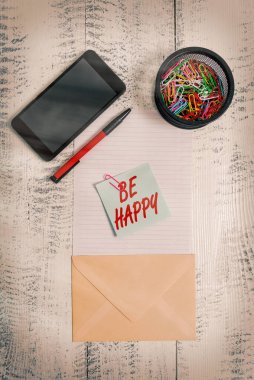 Kelime yazma metni Mutlu ol. Hayatınızın son anı olarak yaşamak için iş konsepti. Smartphone kağıt kağıtları, kalem tutacağı, ahşap arka plan..