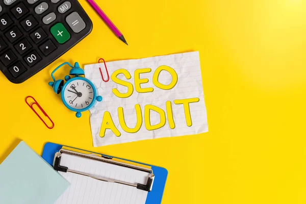 Writing note showing Seo Audit. Business photo showcasing Search Engine Optimization validating and verifying process Alarm clock crushed note calculator pencil clipboard color background.