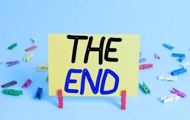 Kavramsal el yazısı The End 'i gösteriyor. İş fotoğrafı metni Oyun İlişkisi etkinliği film eyleminin son bölümü Sonuç Renkli mandal dikdörtgeni şekilli kağıt mavi arkaplan.