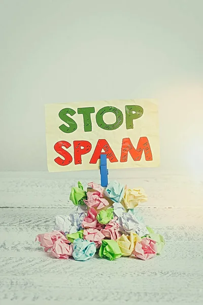 Word writing text Stop Spam. Business concept for end the Intrusive or Inappropriate messages sent on the Internet Reminder pile colored crumpled paper clothespin reminder white wooden space.