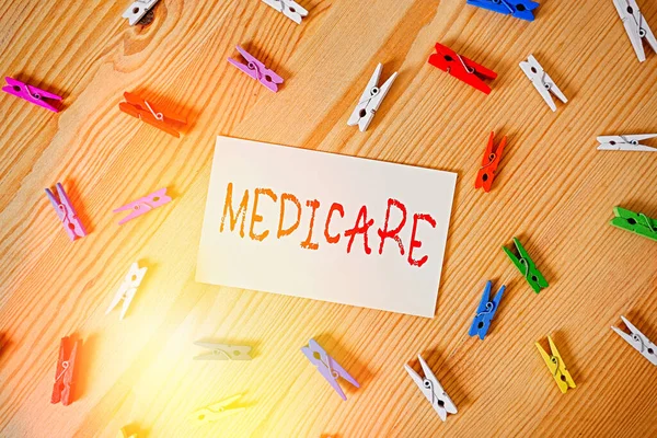 Handwriting text Medicare. Concept meaning the federal government plan in US for paying certain hospital Colored clothespin papers empty reminder wooden floor background office.
