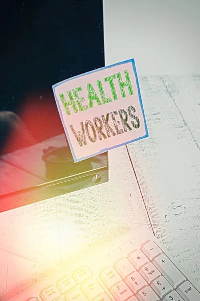Γράμμα που δείχνει τους εργαζόμενους στην υγεία. Επαγγελματική φωτογραφία που δείχνει ποιανού δουλειά είναι να προστατεύει την υγεία των κοινοτήτων τους Σημείωση χαρτί κολλημένο στη μαύρη οθόνη του υπολογιστή κοντά στο πληκτρολόγιο και σταθερό. — Φωτογραφία Αρχείου