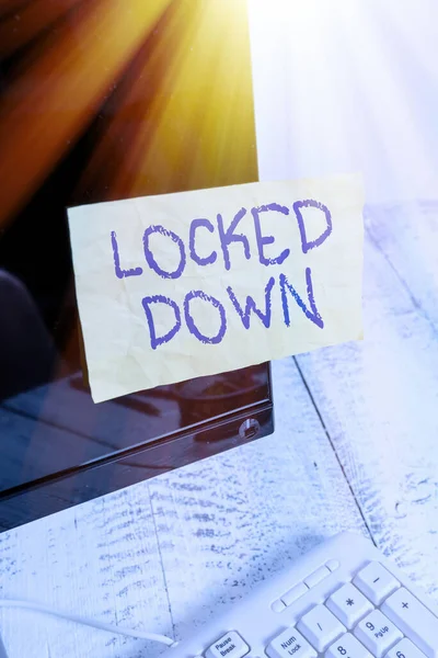 Writing note showing Locked Down. Business photo showcasing emergency measure which showing prevented from restricted area Notation paper computer monitor screen near white keyboard.