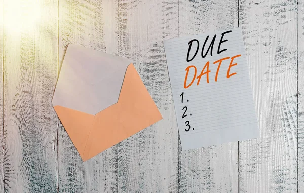 Handwriting text Due Date. Concept meaning The date when payment should be received by the demonstrating or company Front view open colored envelope blank sheet letter paper wooden background.