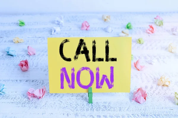 Textzeichen mit Call Now. Konzeptfoto Sofort eine Demonstrantin mit Telekommunikationsgeräten mit Genauigkeit kontaktieren Grüne Wäscheklammer weißer Holzhintergrund farbiges Papier Erinnerung Büromaterial. — Stockfoto